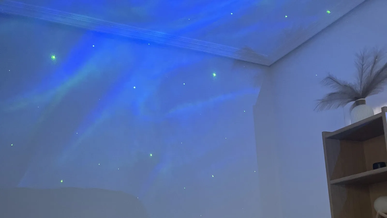 Cabina de masajes de Centro Ónix con un cielo estrellado azul proyectado en el techo y una estantería con un jarrón