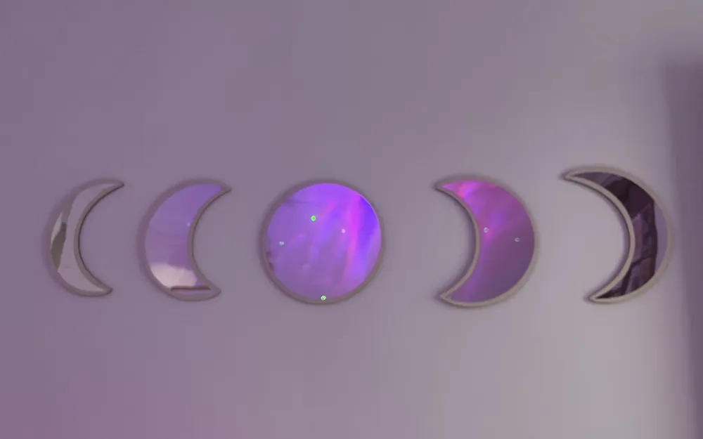 Fases de la luna en espejo sobre una pared lila iluminada